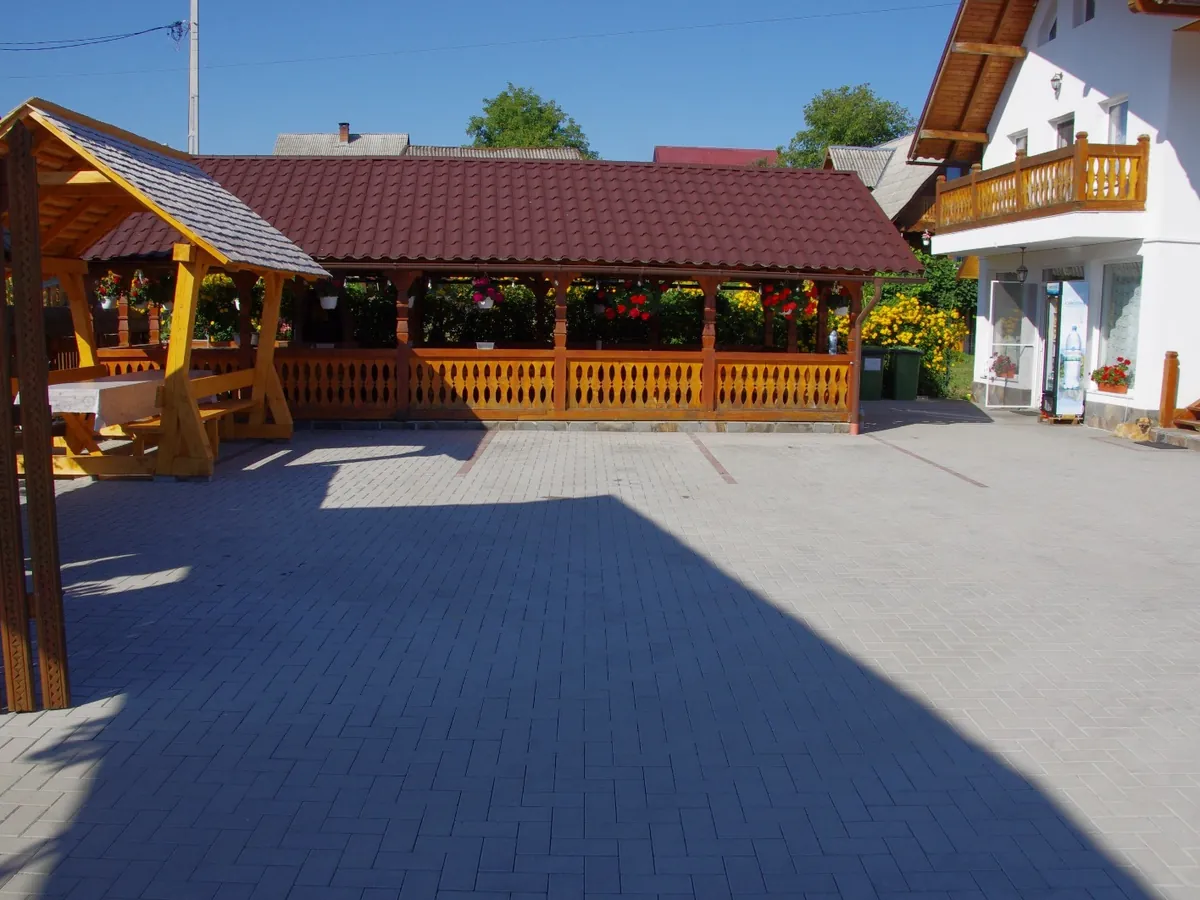 Curtea pensiunii, cu foișorul de lemn și clădirile cu acoperiș roșu